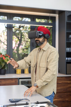 Wireless headphones, vr headset resting on island top under lit pendant light with garden view