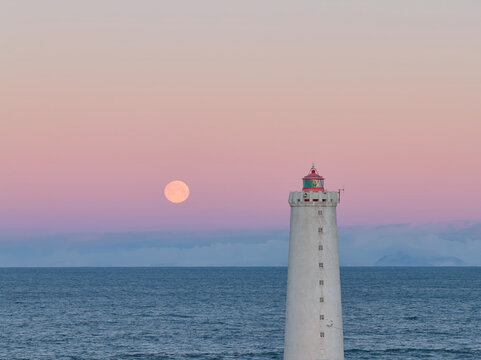 Gr&oacute;tta lighthouse illumined by full moon at dusk in iceland