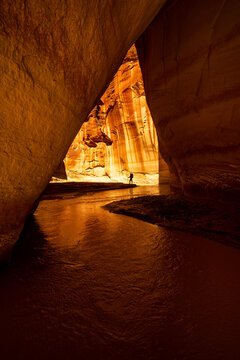 Hiker silhouette inside narrow glowing Paria slot canyon
