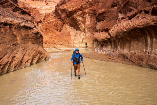 Hiker Wading Through Muddy Utah River Canyon