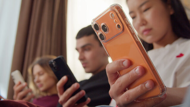 Sad ignore friends sit couch at home living room using smartphone. Addiction social media digital technology, people issue. Cell mobile phone scrolling problem. Useless cellphone internet surfing.