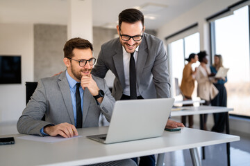 Happy multiethnic businesspeople laughing while collaborating on a new project in an office.