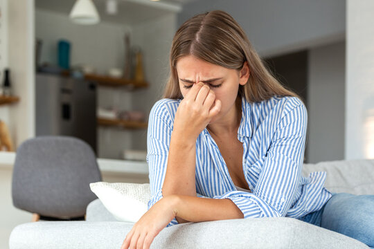 Pain in the eyes. Vision problem and headache, People with health issues, Healthcare And Medicine concept. Attractive woman sitting on the sofa and holding painful bridge of nose with closed eyes.