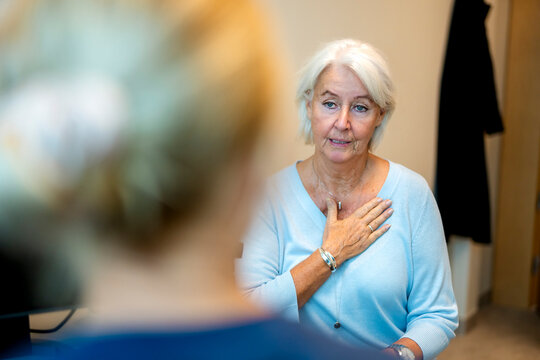 Senior woman explaining chest problems to doctor during hospital visit