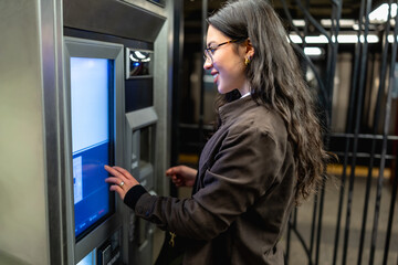 Young businesswoman using subway ticket machine in manhattan