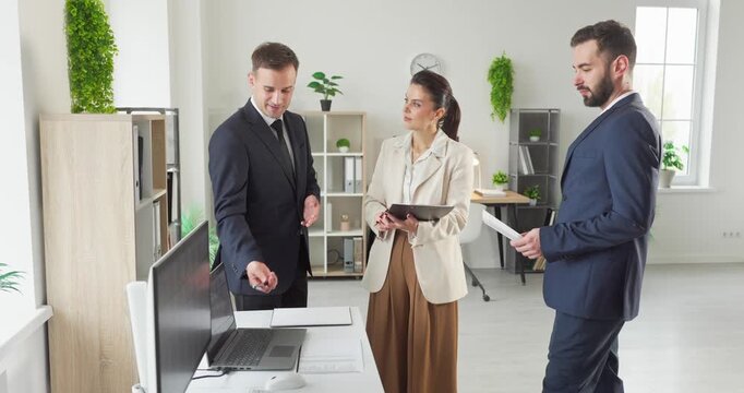 Business team meeting in office planning strategy project. Managers and colleagues align goals on a laptop in a modern workspace, highlighting leadership. Strong teamwork and strategy concept.
