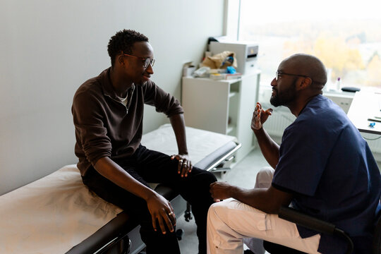 High angle view of male medical professional communicating with patient through sign language while sitting in examinati