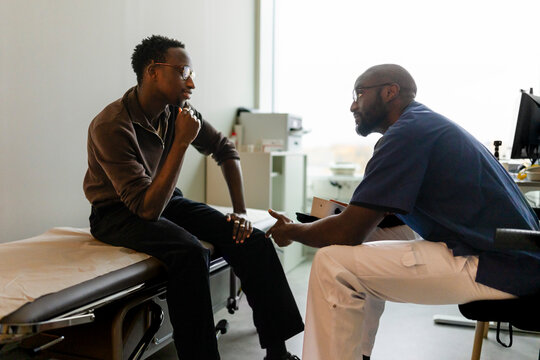 Male medical professional communicating with patient through sign language while sitting in examination room