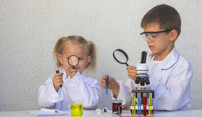 Cute children in lab coats playing with microscope and test tubes