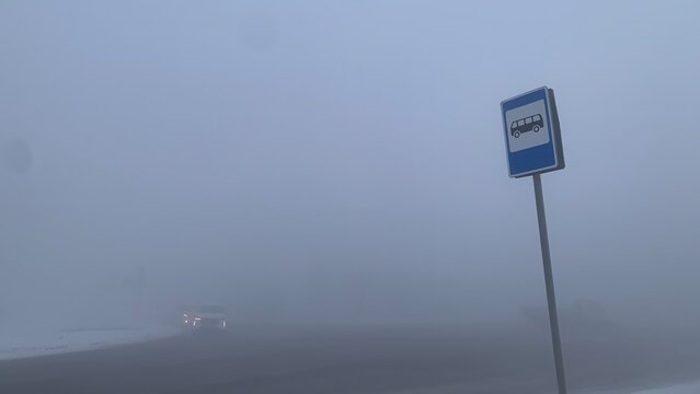 Bus Stop Sign in Dense Fog on Winter Road