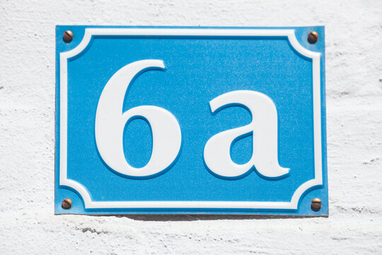 Blaues Hausnummernschild Nr. 6a auf weisser Hauswand, Deutschland
