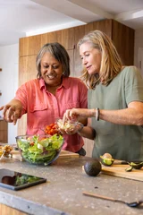 Selbstklebende Fototapeten Zu Kochen Diverse senior friends preparing salad on kitchen island with salad bowl and tablet  © wavebreak3