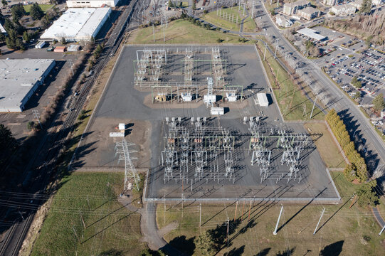 Aerial drone picture of large electric power substation and high voltage power lines in Beaverton, Oregon, showing transmission towers, transformers, and distribution infrastructure from above
