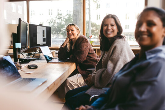 Smiling businesswomen spending leisure time near desk at design company