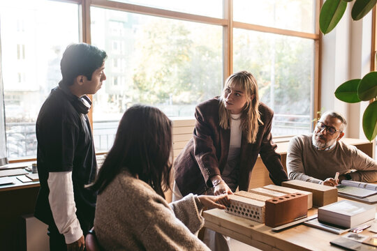 Female creative professional discussing architect project with team in office