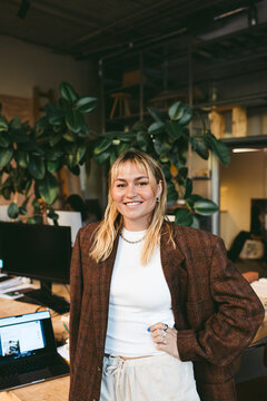 Smiling portrait of female business professional standing with hand on hip in office