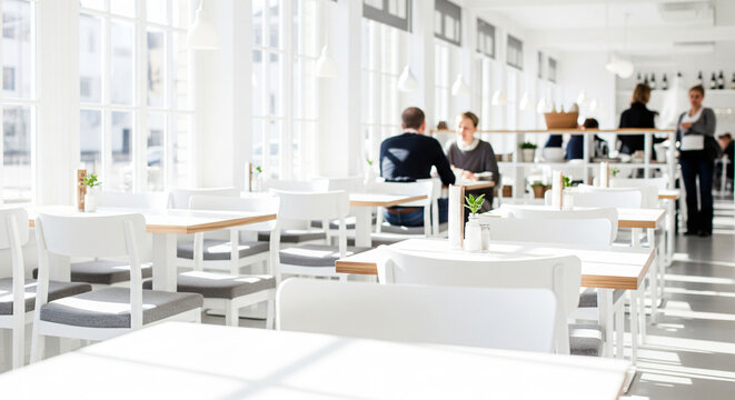 Abstract blurred restaurant background. Blurry cafe or coffee shop with dining tables, chairs and other decorations. Blur backdrop for design element. Food and beverage concept.