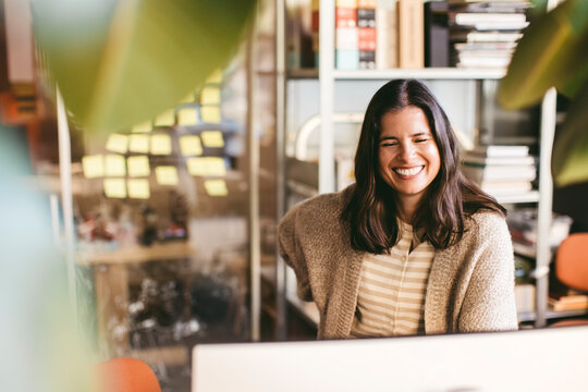 Smiling mature female entrepreneur standing in front of computer at office