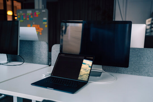 Open laptop kept near computer on desk in office