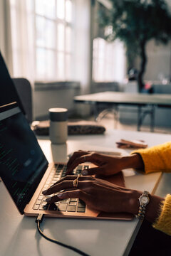 Hands of young businesswoman typing on laptop while working in tech office