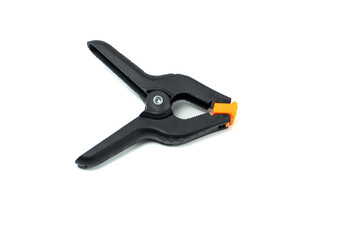 Fototapeta premium Black plastic spring clamp isolated on white background. Adjustable hand clamp tool for woodworking, DIY projects, photography studio and workshop use.