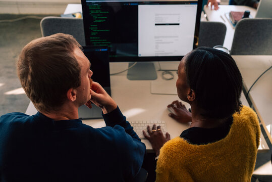 High angle view of male and female business professional working on computer at desk in tech office