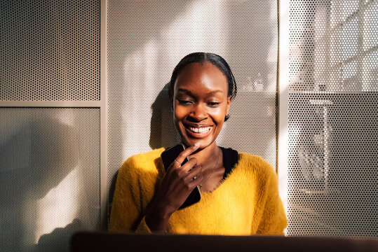 Smiling short haired businesswoman with hand on chin holding smart phone
