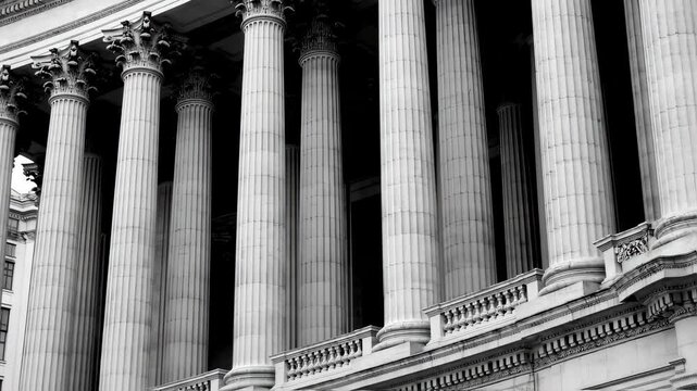 Black and white image of a grand building facade, featuring a row of tall, fluted columns