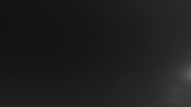 Soft grayscale gradient from dark right to lighter left, with faint out-of-focus light blurs. across