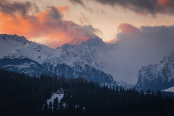 Scenic winter landscape of the Tatra Mountains at dawn. Snow-covered peaks and frosty pine forests under a crisp blue morning sky.