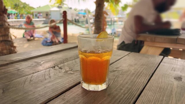 The refreshing, iced orange cocktail with a straw while relaxing in the shade under palm trees on a beach on the island of St. Maarten. Saint Martin is an island in the northeastern Caribbean.