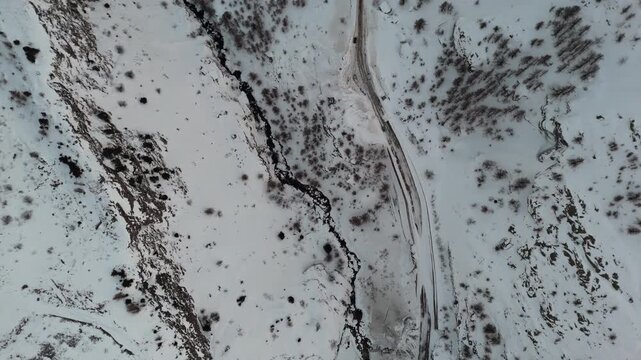 Aerial view of snowy landscape with river, serene and winter-themed
