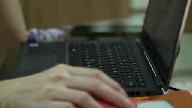 close up of laptop with foreground hand holding mouse