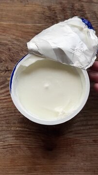 Open Greek yogurt on wooden background, top view