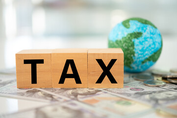 Global Minimum Tax or Global Minimum Corporate Tax concept. A globe and word tax on money banknote.