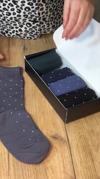 A woman examining a set of men's socks in different colors. Packaged in a box. Making a purchase review. Vertical video.