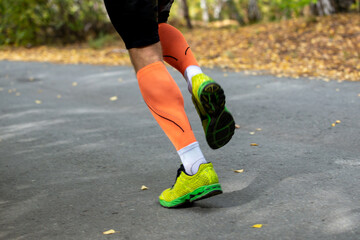 Legs male athlete in compression socks running race in park