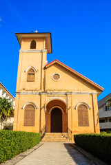 Fototapeta premium Beautiful vintage yellow Christian church architecture with cross symbol against blue sky background.