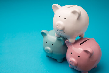 White, green, pink three piggy banks on blue background copy space. Financial planning management, money literacy, savings, personal wealth, money saving, banking finance and so on concept.