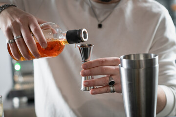 Bartender pouring whisky into shaker to make pineapple whisky sour. Captures flow, amber color, and...