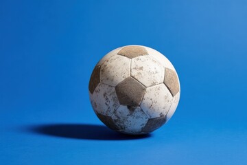 Fototapeta premium Weathered soccer ball on vibrant blue background