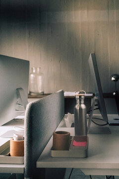 Mugs and insulated drink container kept near computer on desk in office