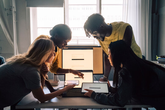 Female and male creative professionals comparing software on different devices while working in tech office