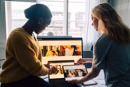 Female tech professionals checking software design preview by comparing them on different devices in office