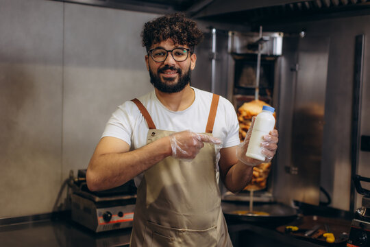 Kebab shop worker holding ayran bottle