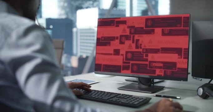 In Office Male Worker Uses a Desktop PC as Network Get Virus and Malware Infeceted, Display Showing Covers His Charts,  System Hacked Skull Fills the Screen, Showing Ransomware