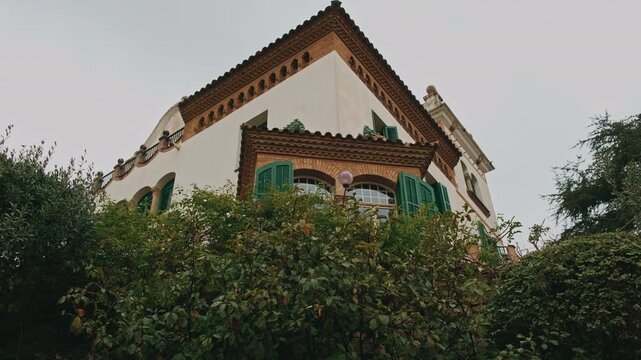 White Villa With Green Shutters, LowAngle Composition Highlighting Gabled Roof And Terracotta Tiles, Stone Retaining Wall
