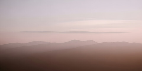 Obraz premium Ethereal layers of mountains shrouded in fog at dawn