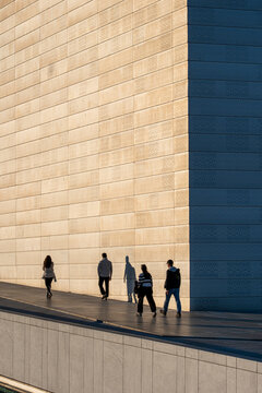 Silhouette on walkway beside modern wall in Oslo Norway Barcode showing architecture minimalism and long shadow across quiet plaza today