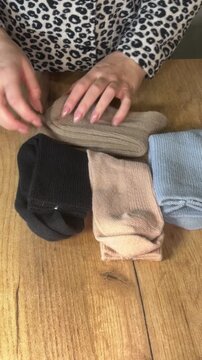 A woman examining a set of socks in different colors. Making a purchase review. Vertical video.